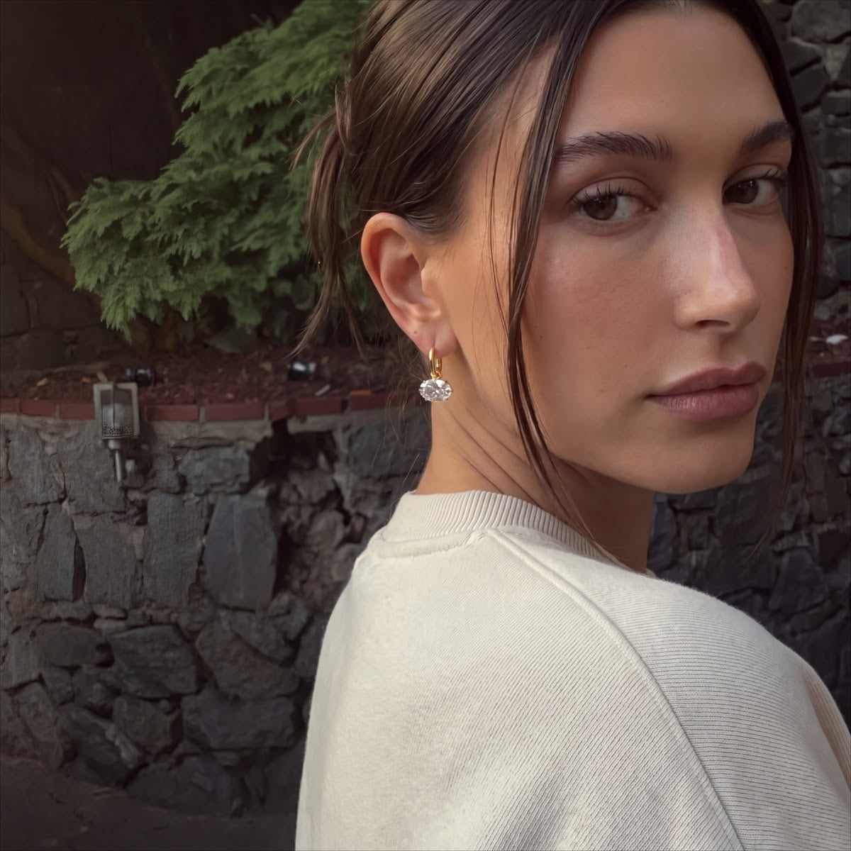 A pair of Hailey Earrings held in a hand